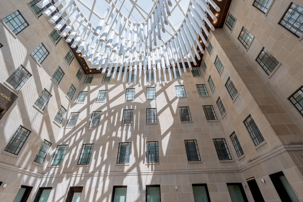 The glass ceiling and chandelier in the grand hall at the West Memorial Building. The sun is shining through the glass ceiling and casting shadows of the chandelier on the walls.