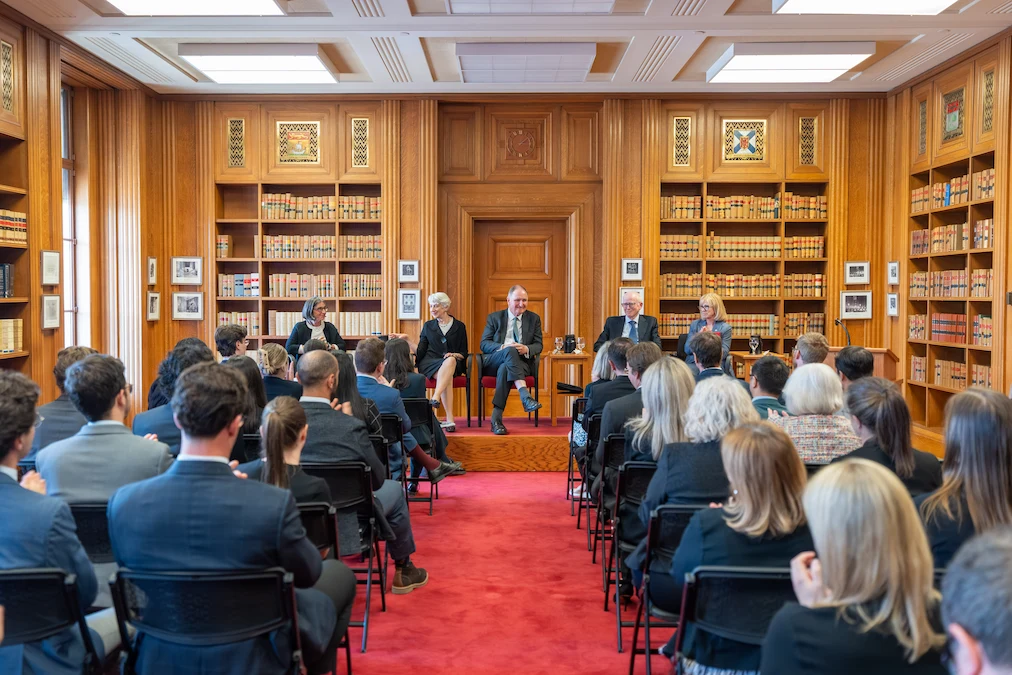 The delegation from the United Kingdom Supreme Court seated on a stage while staff members listen